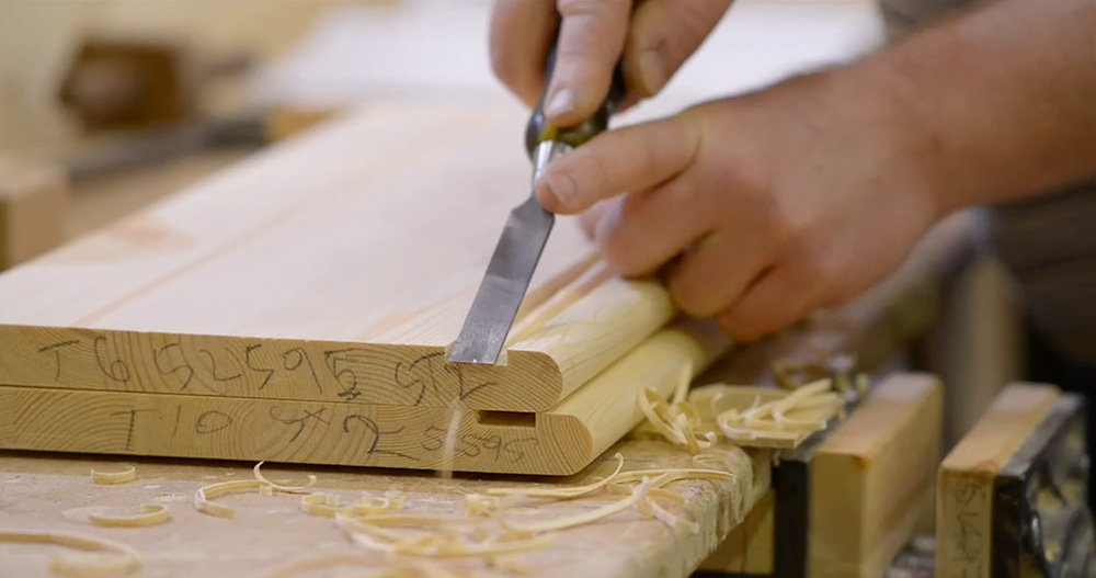 Detail work on a stair tread using a hand chisel during staircase assembly